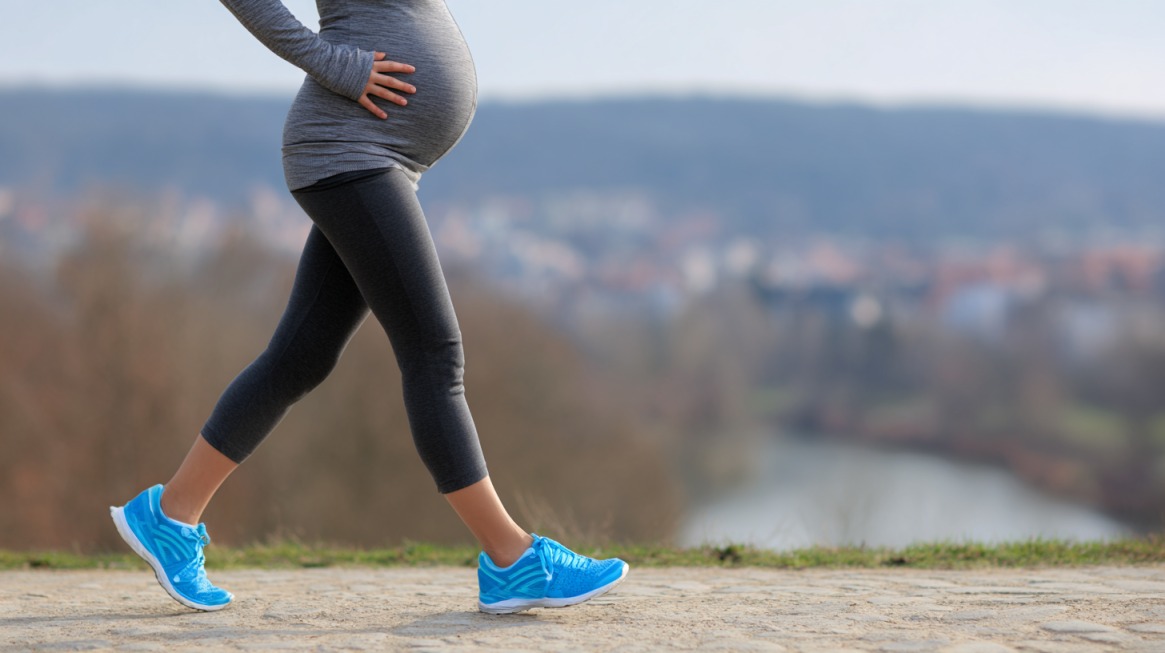 Trudnica šeta na otvorenom i drži ruku na stomaku